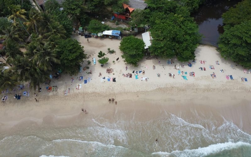 Stunning aerial view of Hiriketiya Beach, Sri Lanka, showcasing sunbathers and lush greenery.